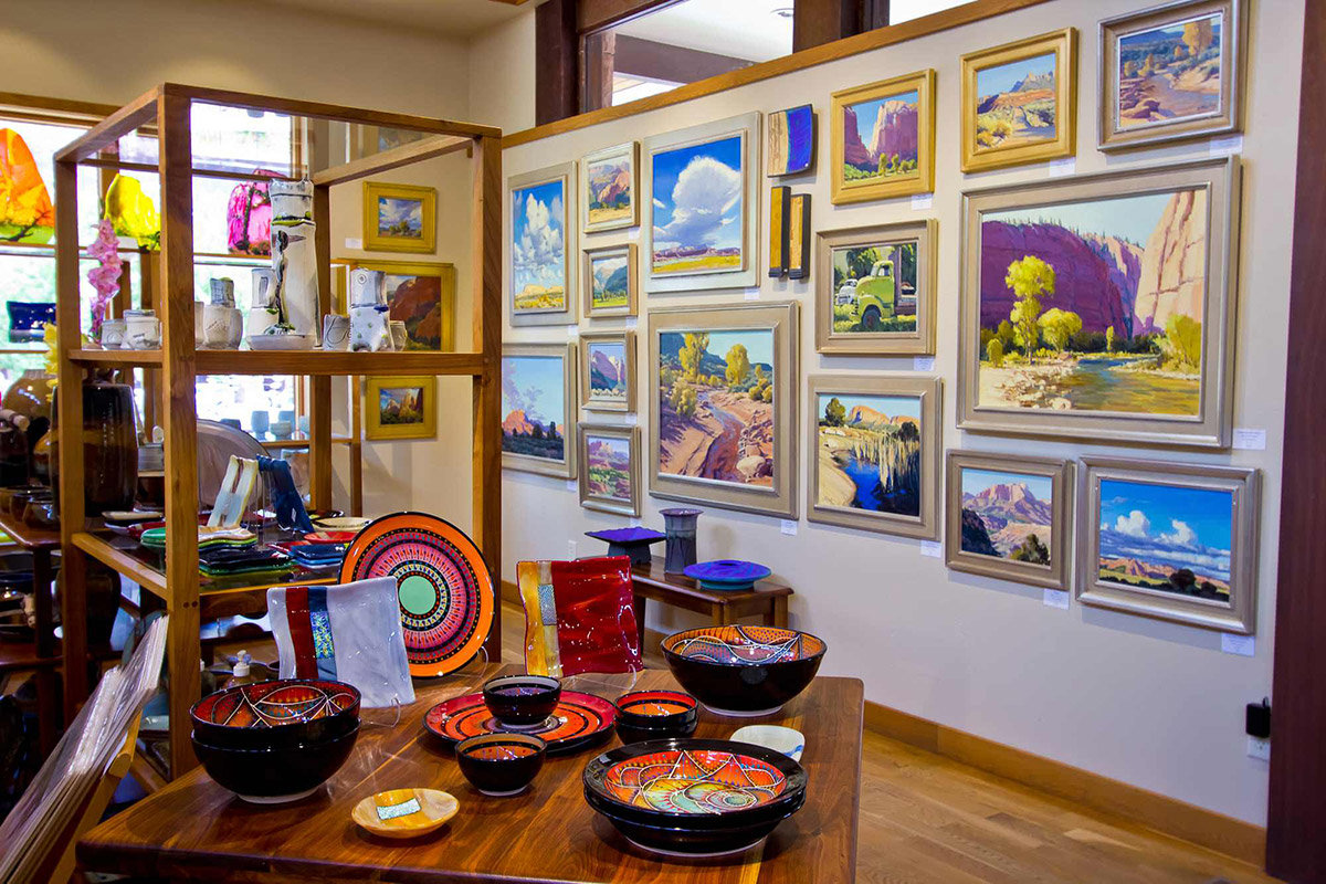 Collage of brightly-colored paintings on gallery wall with decorative bowls in foreground