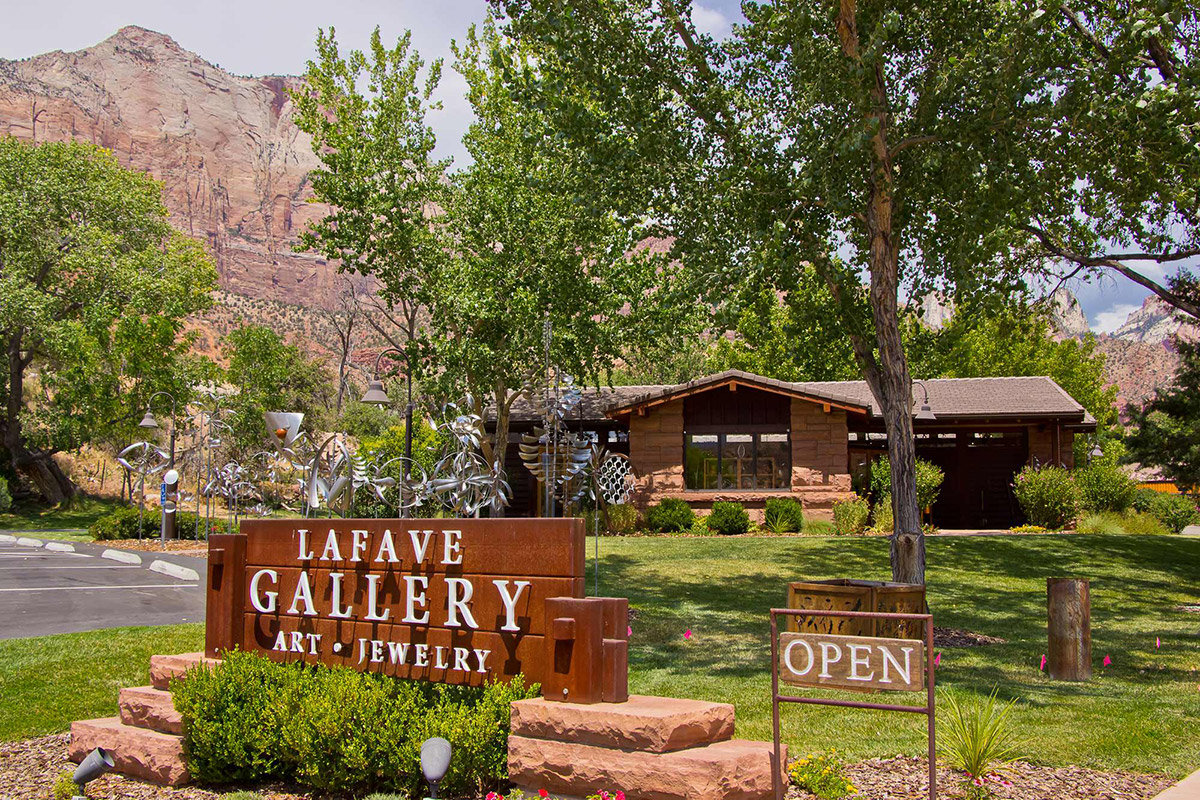 Sign reading LaFave Gallery in front of building with trees and large mountain behind