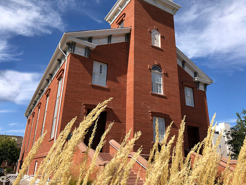 View of the red brick church building through blades of grass