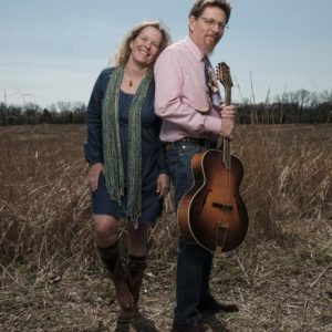 Tim and Jan standing in a field, holding a guitar